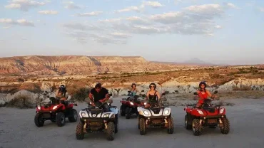 Sunset Quad Safari Trip Marsa Alam with riders crossing golden dunes against a glowing orange sunset sky