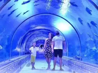 Visitors walking through the underwater tunnel at Hurghada Grand Aquarium surrounded by colorful marine life