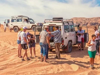 Super Safari Trip Marsa Alam with tourists riding quad bikes across golden desert dunes at sunset