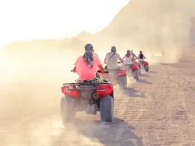Sunset Quad Safari Trip Marsa Alam with riders crossing golden dunes against a glowing orange sunset sky