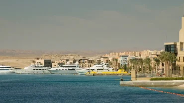 Port Ghalib shopping area with colorful boutiques, waterfront cafes, and tourists browsing souvenirs